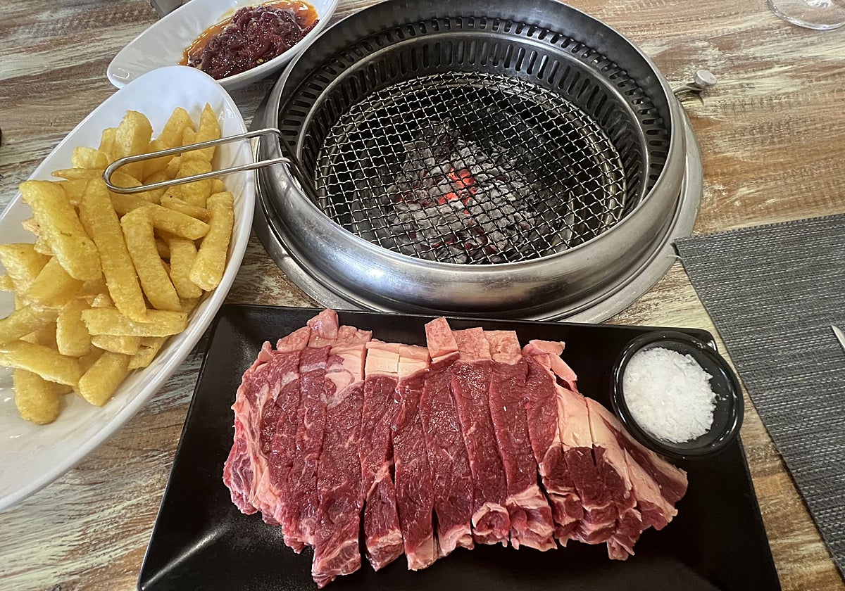 Parrilla coreana con carbón vegetal y extracción de humos por un conducto que sale por debajo de la mesa.