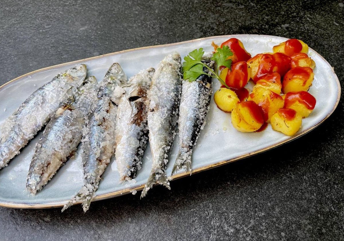 Las sardinas a la sal, preparadas para disfrutarlas, con unas patatas con salsa picante.