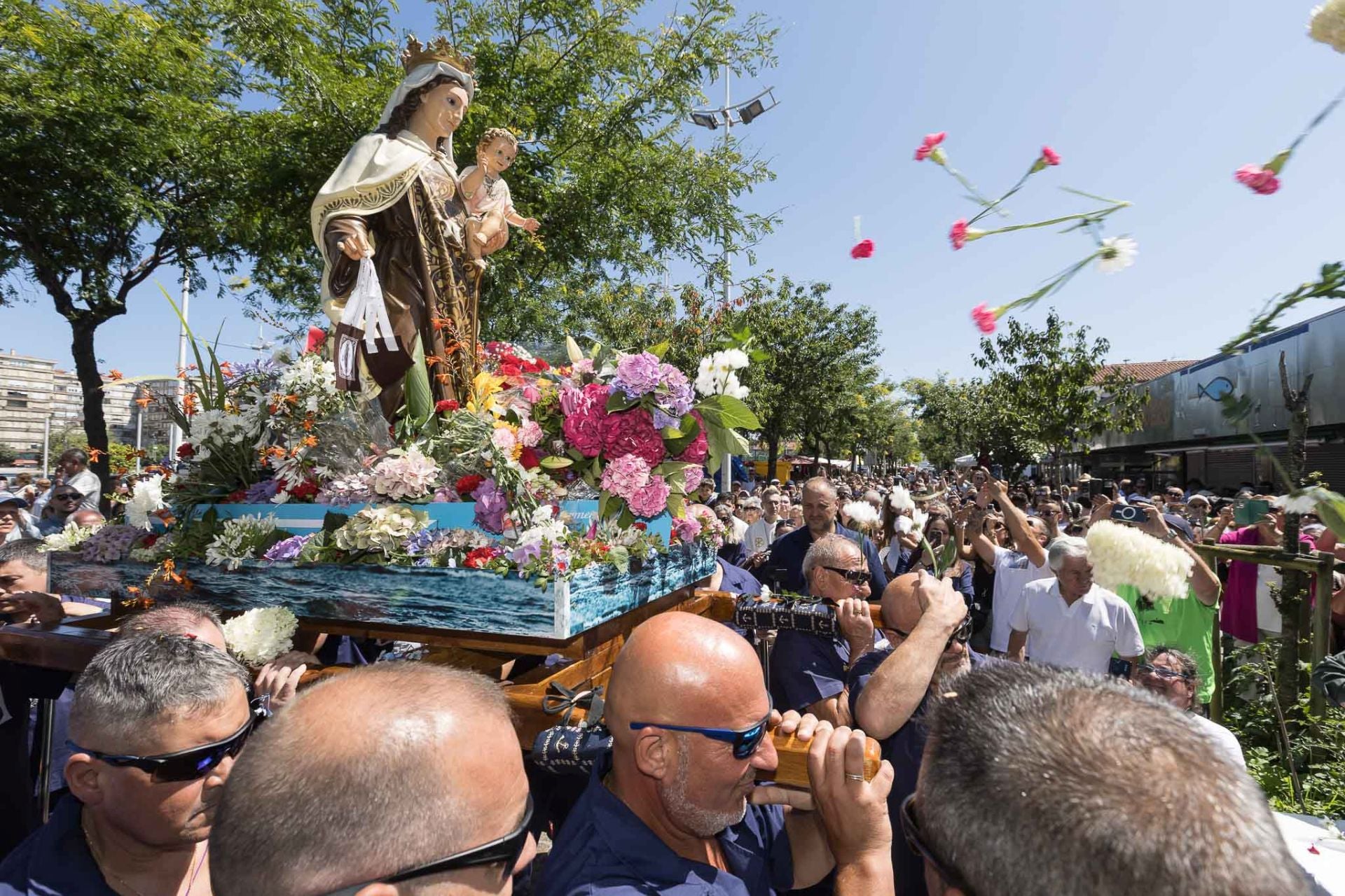 Los asistentes lanzan flores a la Virgen del Carmen. 