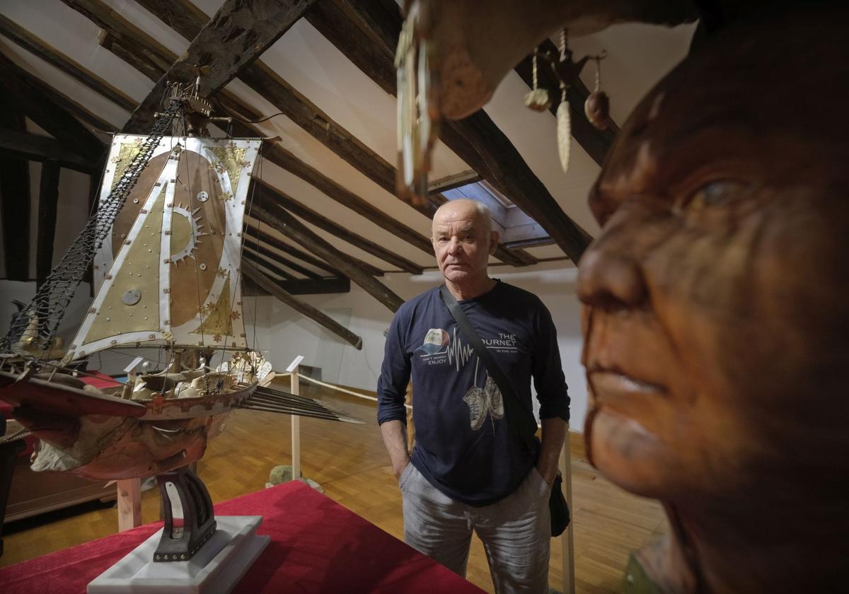 Manuel Díaz Ceballos, junto al barco realizado con hueso de animal y el retrato que porta una máscara.