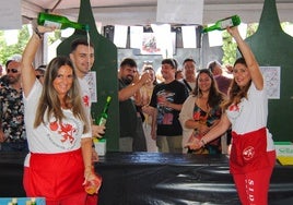 Dos voluntarias escancian la sidra para ofrecérsela al público congregado.