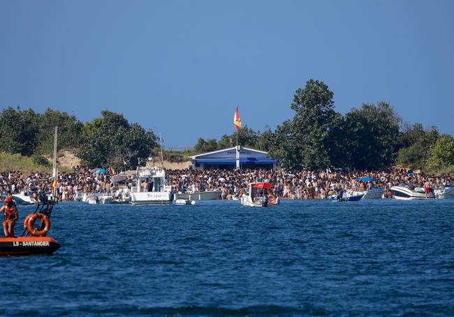 Cientos de personas se arremolinan junto a uno de los chiringuitos de la playa.