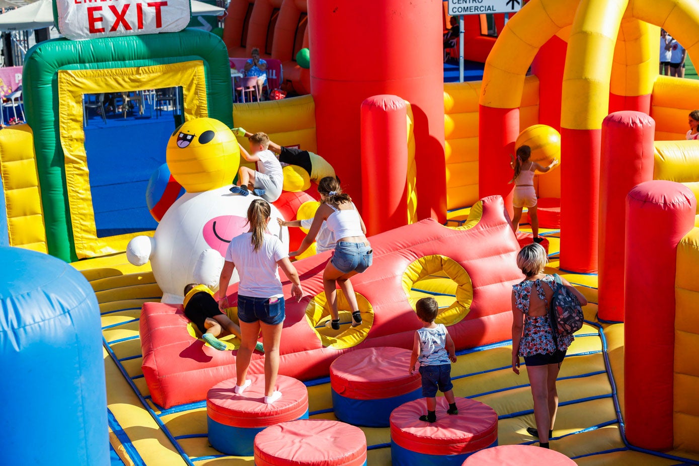 Jóvenes y niños saltando obstáculos hinchables y jugando