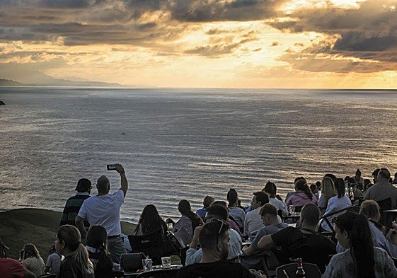 Las numerosas personas congregadas en El Rayo Verde contemplan con expectación el momento de la puesta del sol.