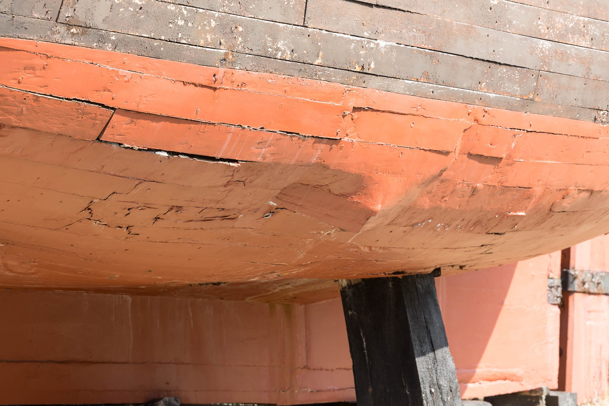 Primer plano del estado de la madera, hinchada por las inclemencias del tiempo y con la pintura levantada.
