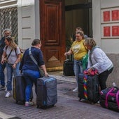 Un grupo de turistas carga con maletas a la entrada de una vivienda de uso turístico.