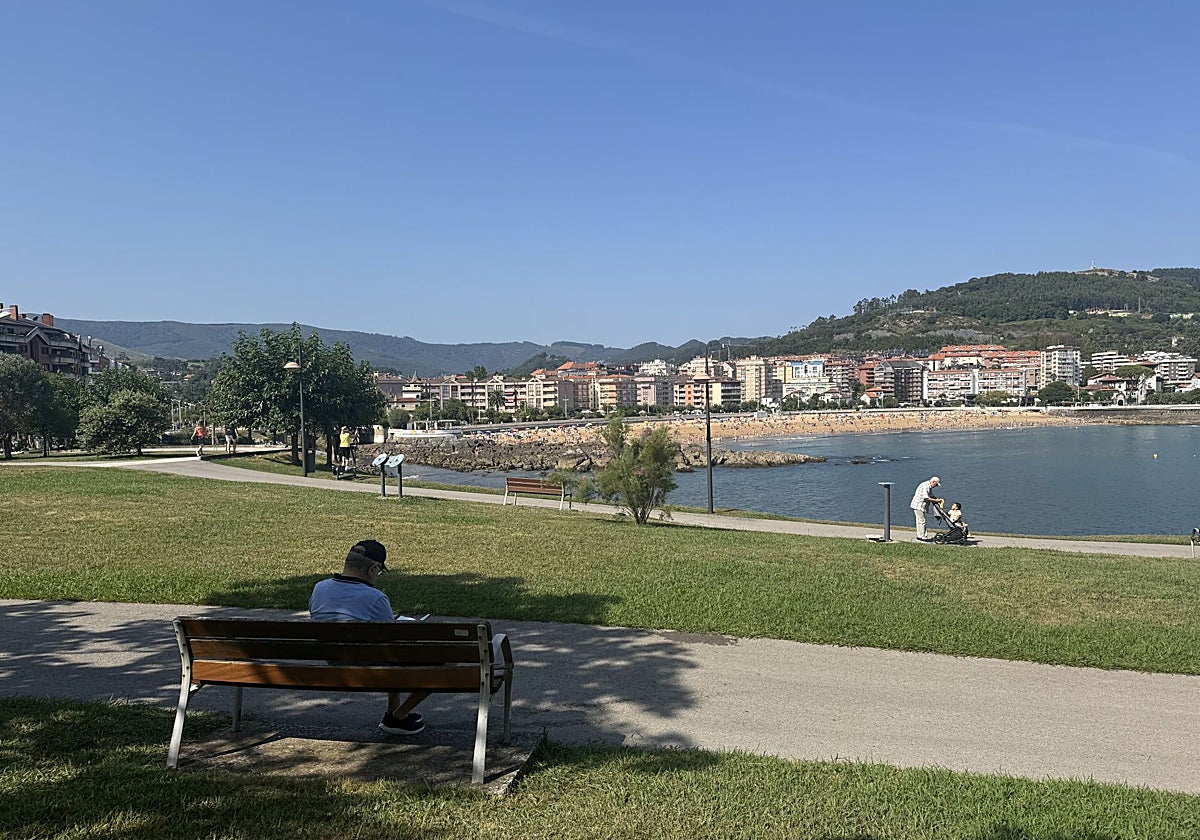 Un hombre lee sentado en un banco del parque de Cotolino de Castro Urdiales.