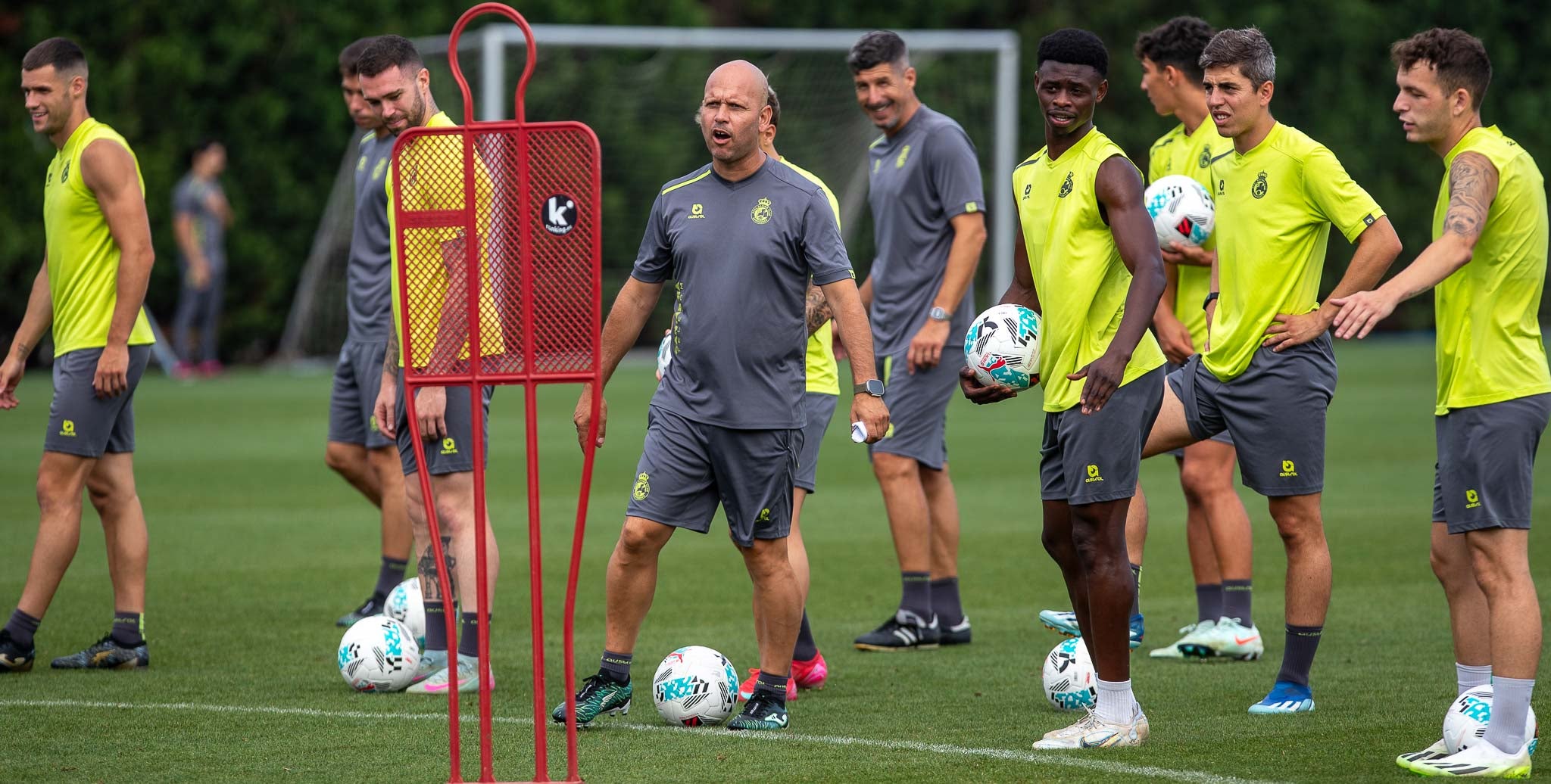 El técnico da indicaciones rodeado por sus jugadores.