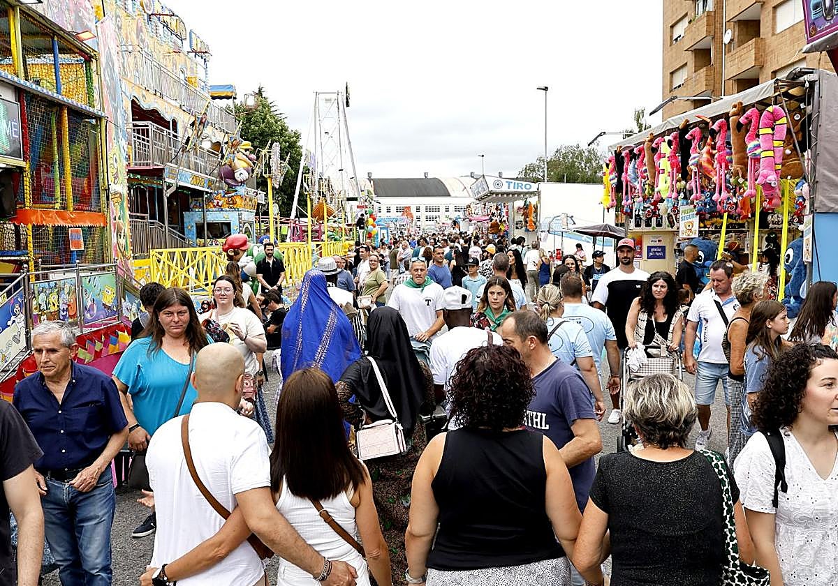 Cientos de personas caminan frente a los puestos y las atracciones del recinto ferial, en el barrio de El Zapatón de Torrelavega.