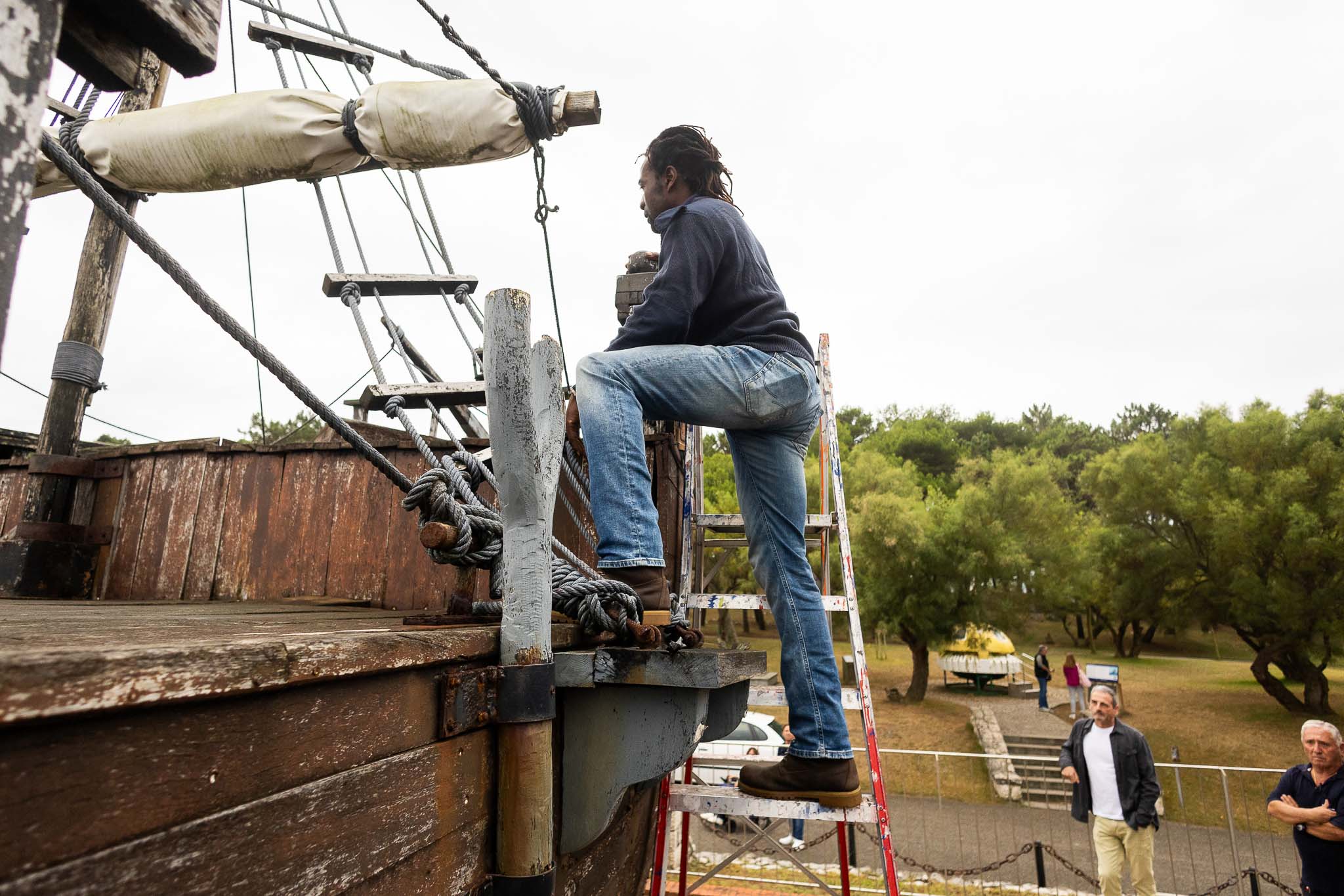 Con la ayuda de una escalera, Abaga sube a las cubiertas de los barcos para analizar en qué estado se encuentran.