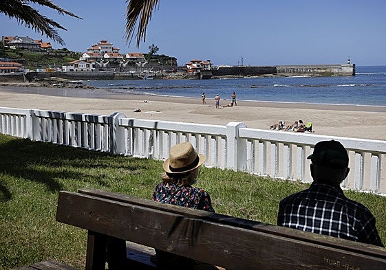 Dos personas en uno de los bancos de la zona de los pinares, junto a la playa de Comillas.