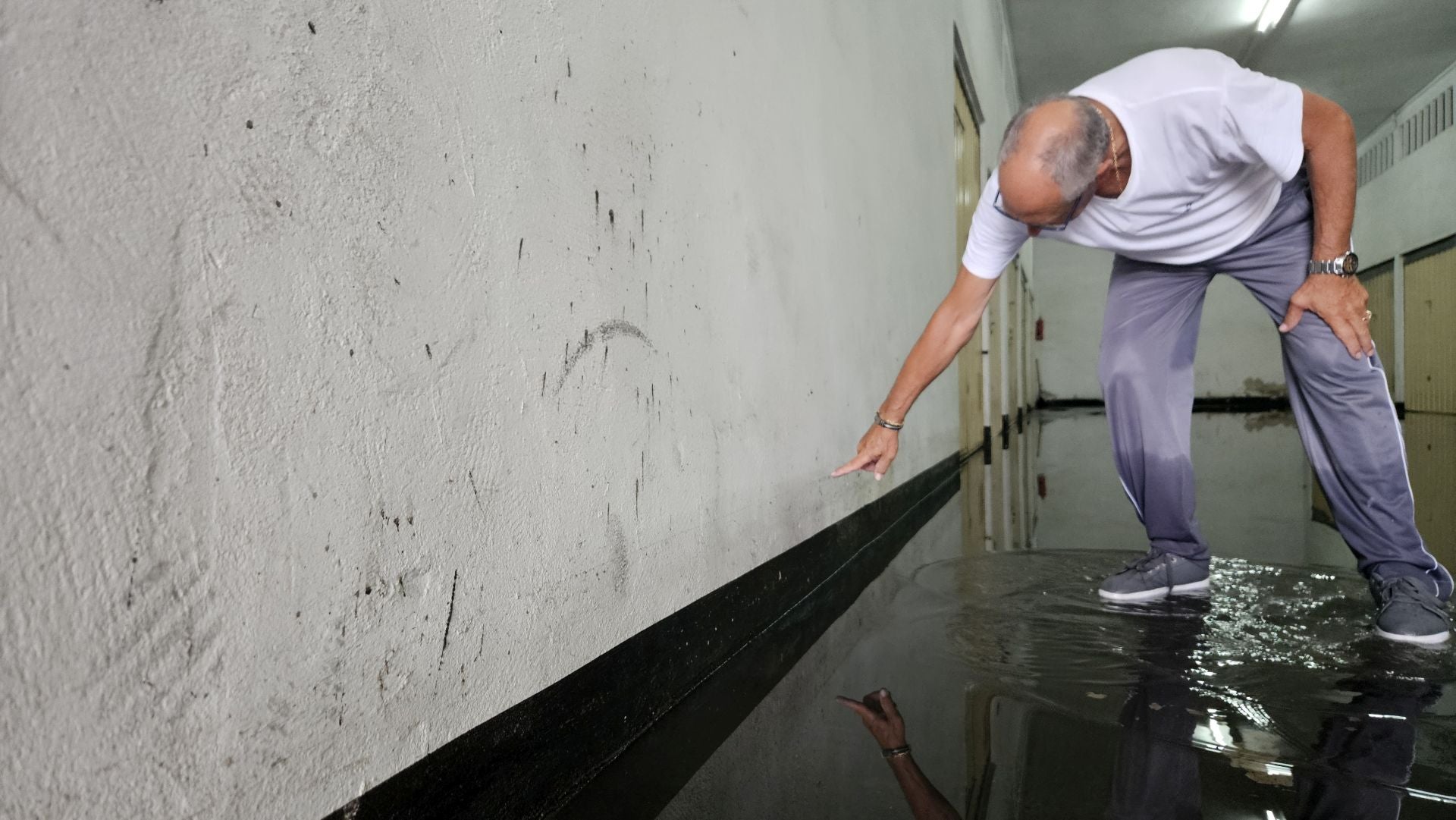 Un propietario señala el punto hasta dónde llegó la inundación en el garaje de la comunidad