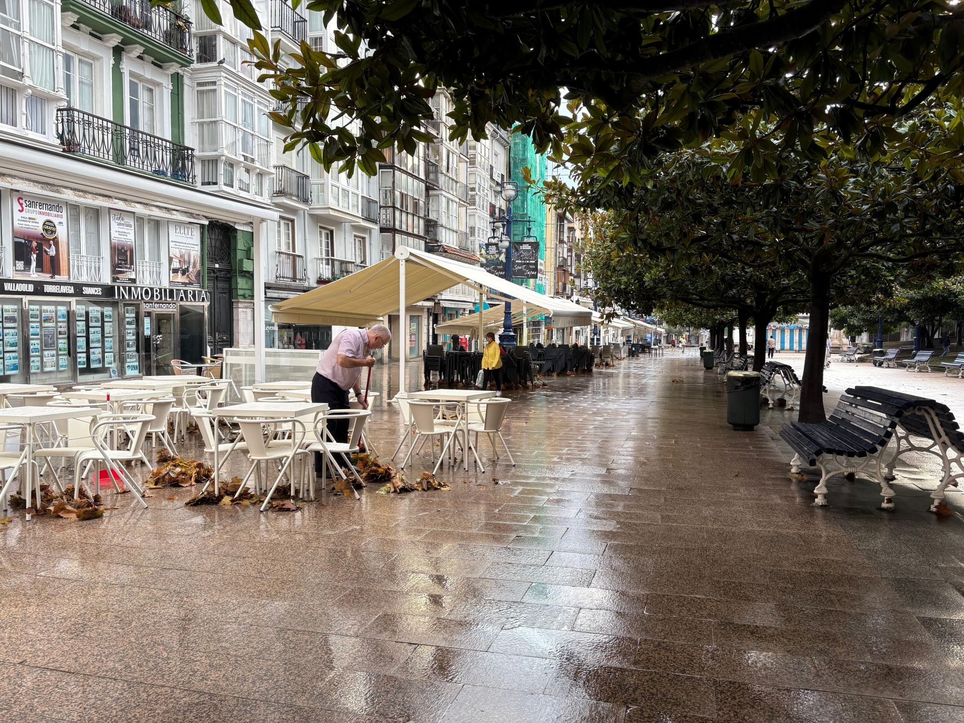 Un hostelero barre la hojarasca para evitar que la terraza se inunde 