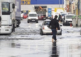 Un hombre camina con el agua a la altura de los tobillos en el polígono de Candina de Santander.