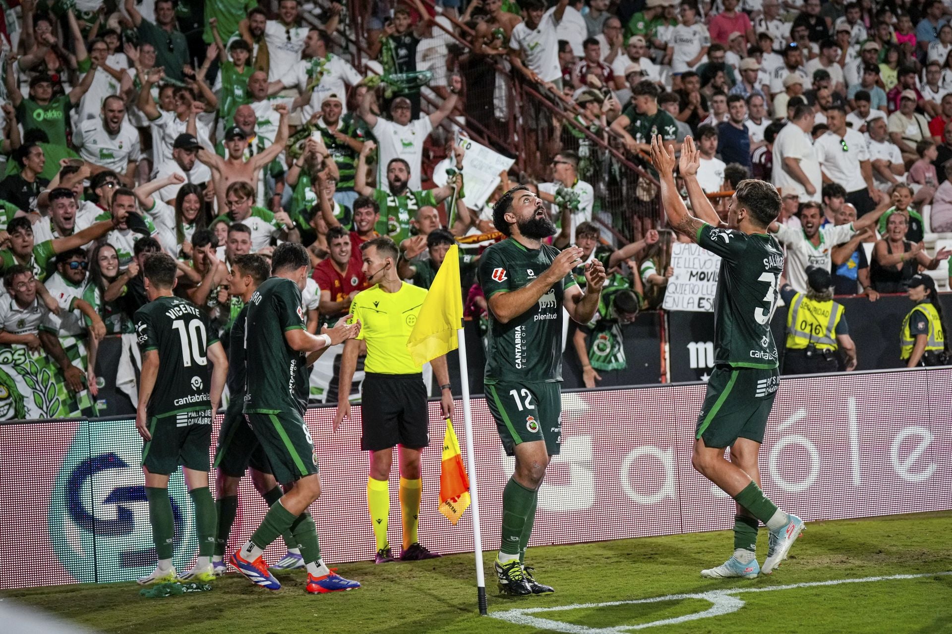 Los jugadores del Racing celebran junto a la afición el tercer tanto verdiblanco. 