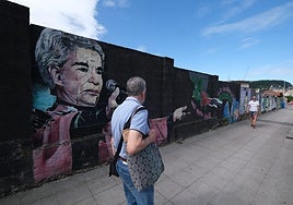 Vecinos caminan junto al mural de arte urbano junto al Ferial de Ganados, en Torrelavega.