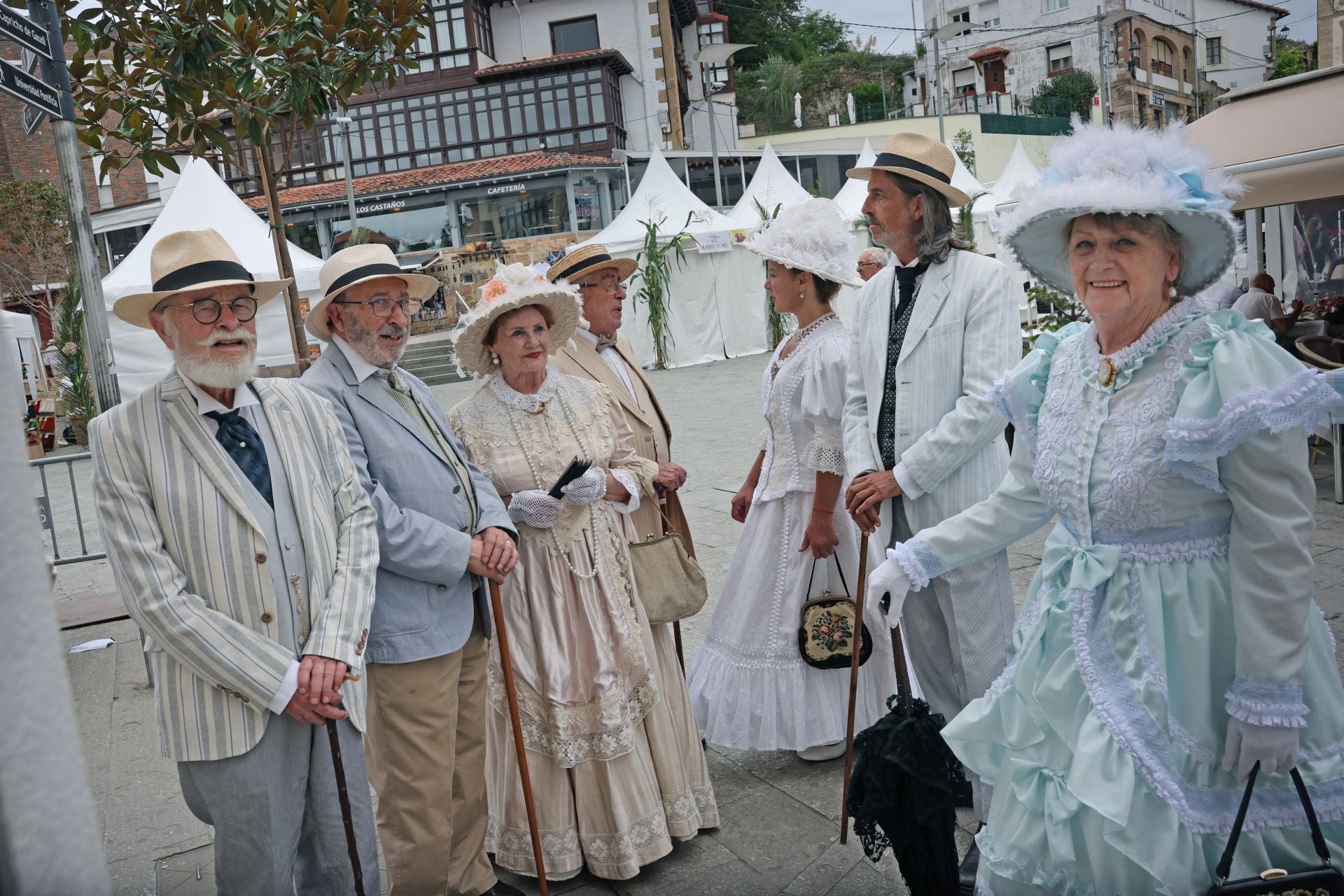 Hombres y mujeres lucen sus sombreros del siglo XIX en la plaza del Corro de Comillas.