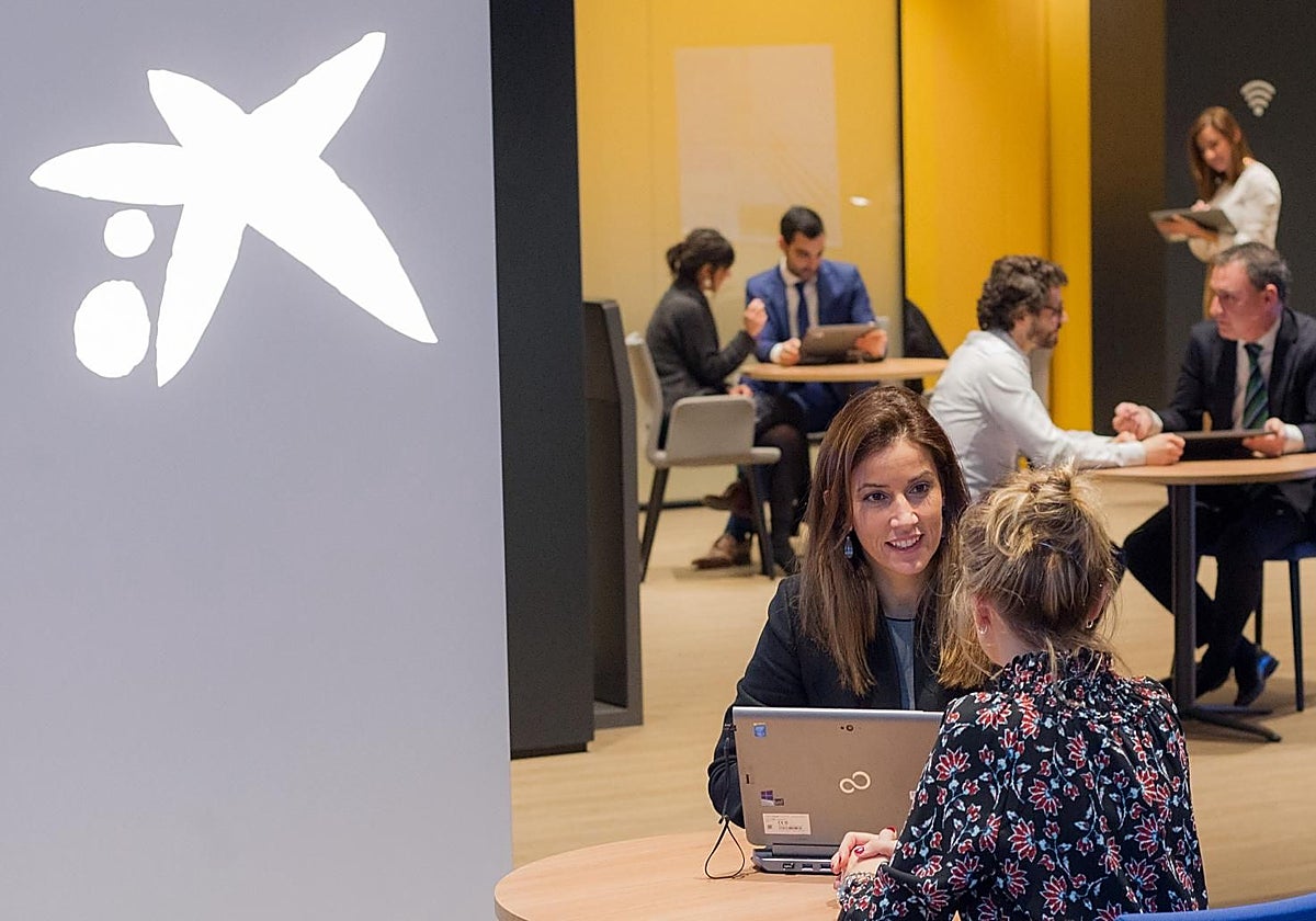 Clientes y trabajadores en una oficina de Caixa.
