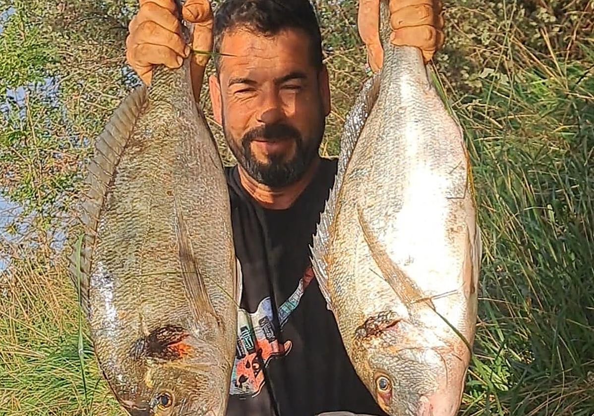 Iván Agudo posa junto con las dos doradas capturadas en la ría de Cubas.