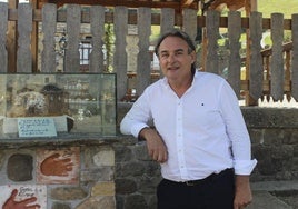 El alcalde de Vega de Pas, Juan Carlos García Diego, junto al monumento al sobao en la plaza del pueblo.