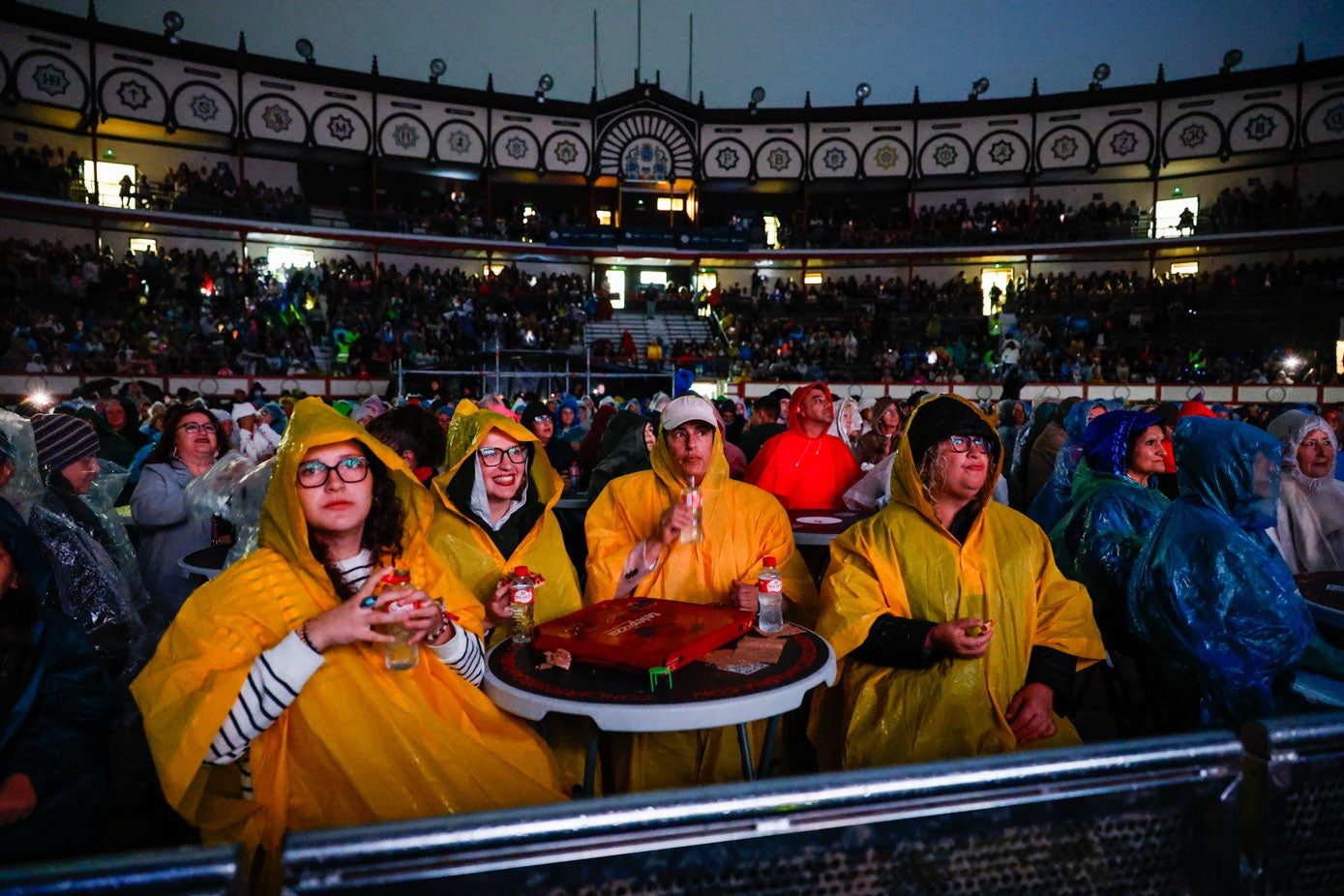 Los asistentes se refugiaron de la lluvia con chubasqueros.
