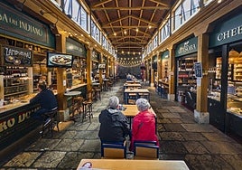 Varios clientes, sentados en la terraza de la Casa del Indiano, dentro del Mercado del Este, ubicado en el centro de Santander.