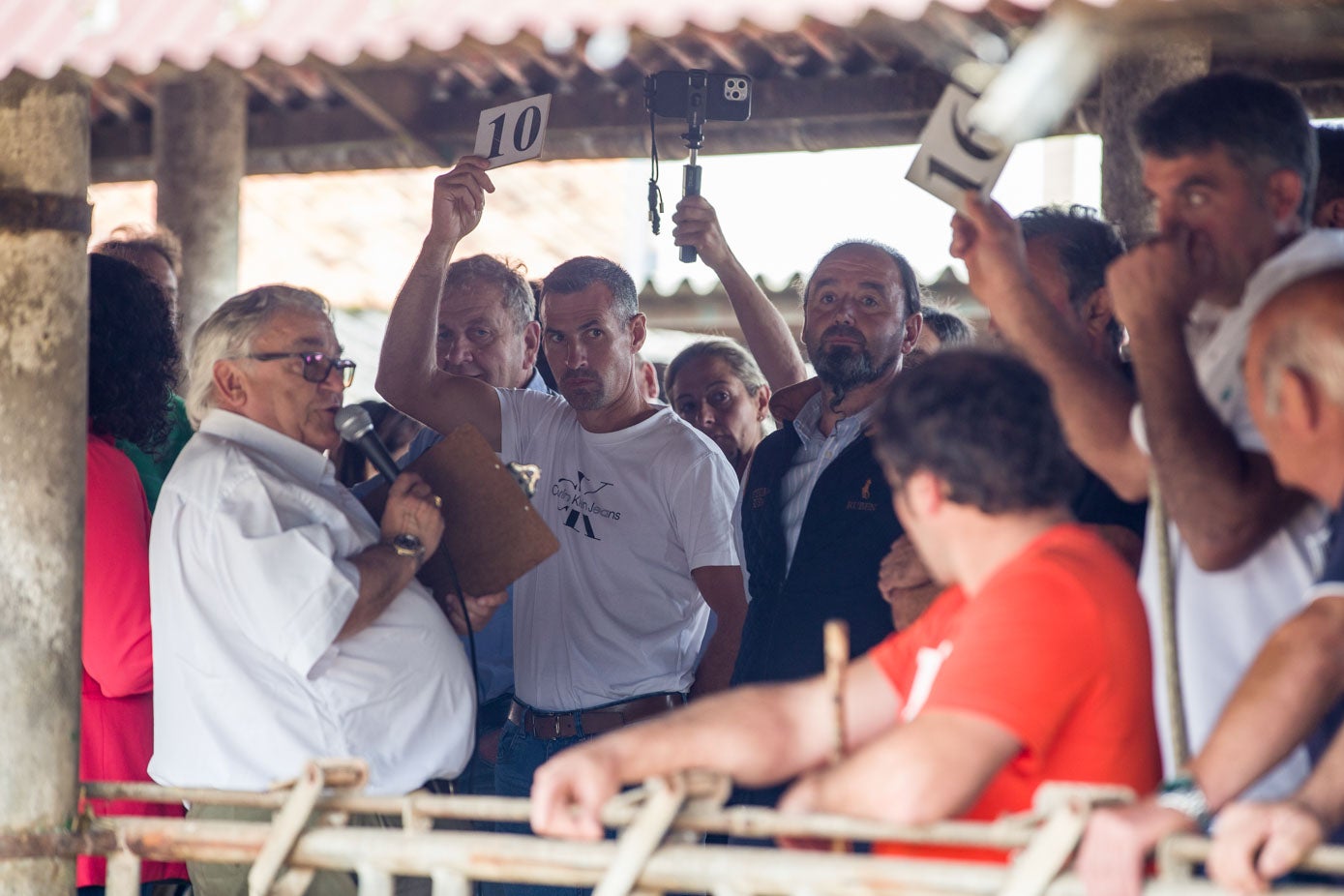 Los participantes en la subasta alzan sus fichas para pujar.
