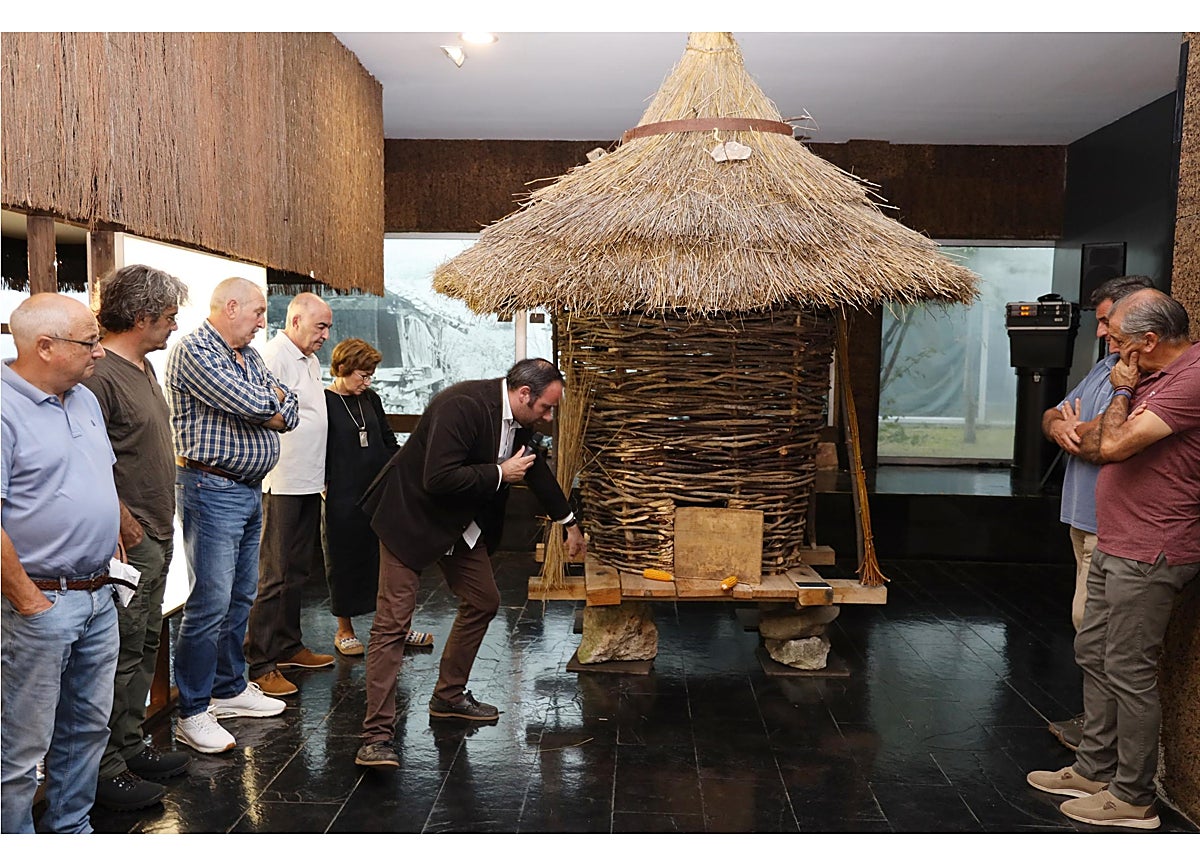 Imagen secundaria 1 - Pilar Gómez Bahamonde durante su intervención; el Canasto de Baras, portugués, que se muestra en la exposición, y el alcalde de Cillorigo de Liébana, Jesús Cuevas, contemplando la maqueta del hórreo cántabro de Anievas