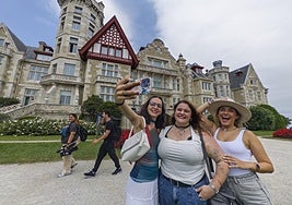 Tres turistas se hacen un selfie junto al Palacio de La Magdalena, en Santander.