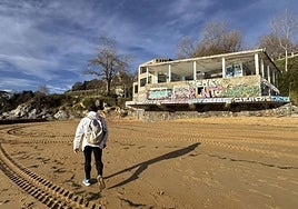 Un hombre pasea por la playa de Los Peligros, junto al edificio abandonado de La Horadada.