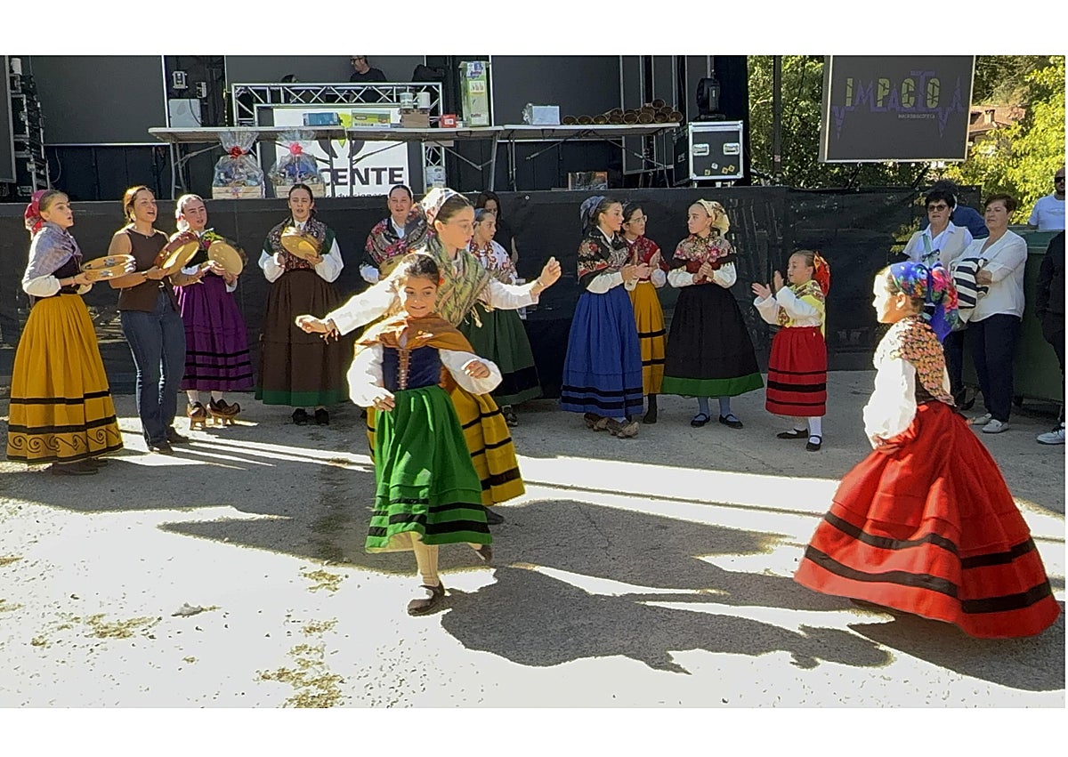 Imagen secundaria 1 - Un puesto con productos de la huerta, las niñas del Aula de Cultura Tradicional del Valle de Camaleño, bailando junto al escenario, y una de las afortunadas con la cesta de productos de Liébana