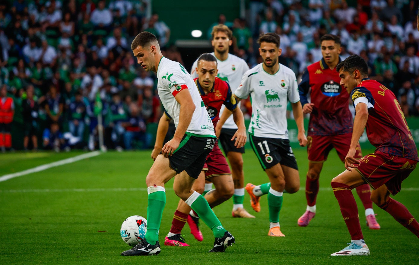 Mantilla conduce el balón ante la presion de dos rivales.