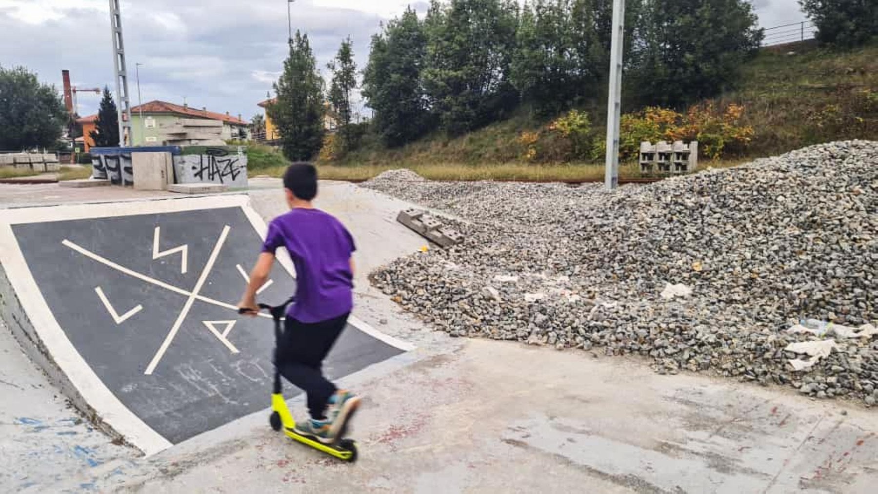 Un joven recorre las pistas de La Lechera con su patinete, el pasado domingo, junto a la obra del desvío del tren, en Torrelavega.