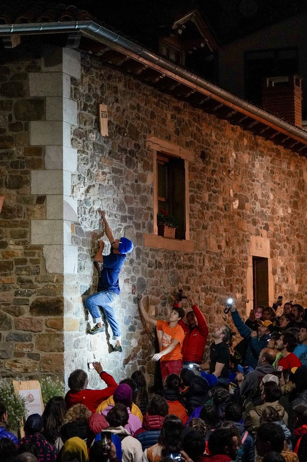 Un escalador, en la fachada de un edificio en Potes.