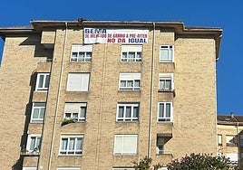 Un hombre en el tejado coloca el cartel que critica la actuación del Ayuntamiento.