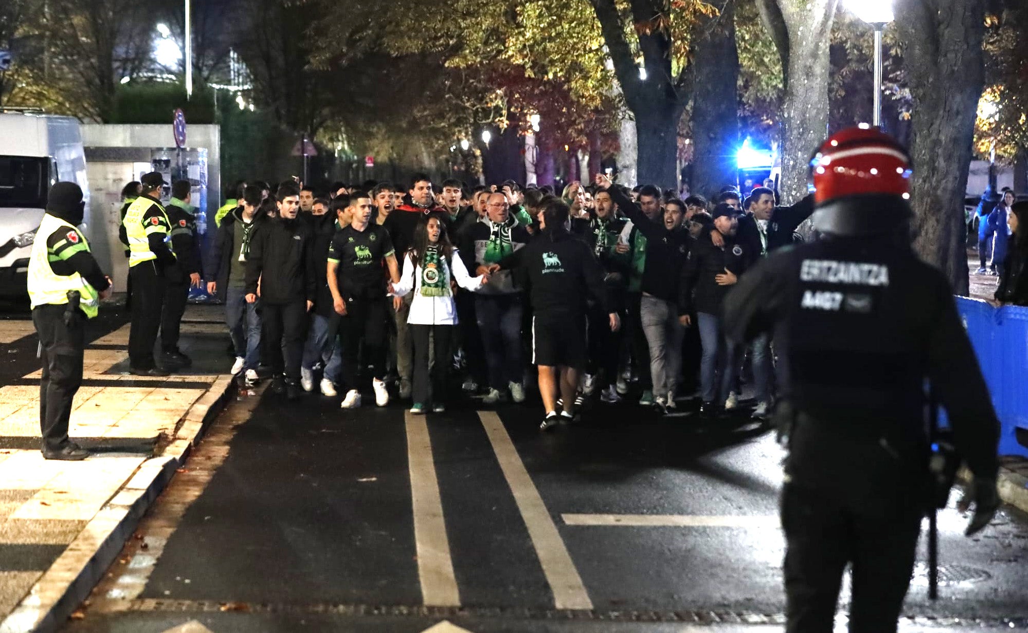 Un grupo de aficionados del Racing, rodeado de personal de seguridad y agentes del la Ertzaintza