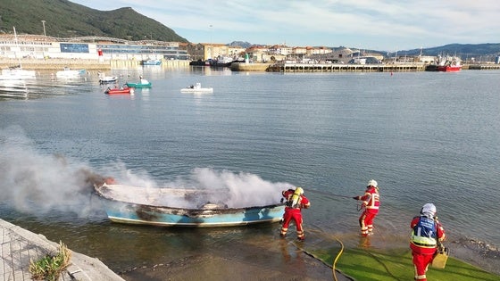 Los bomberos del 112 sofocan las llamas de la embarcación.