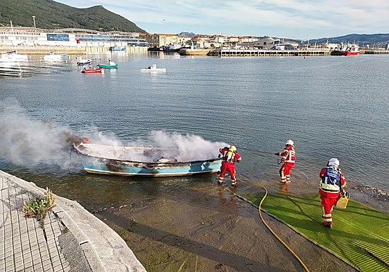 Los bomberos del 112 sofocan las llamas de la embarcación.