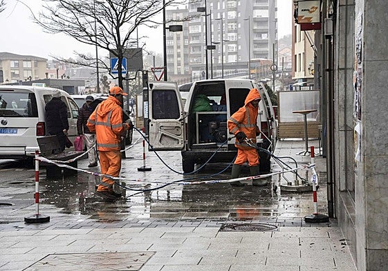 Dos operarios realizan la limpieza de aceras en una calle de Maliaño.