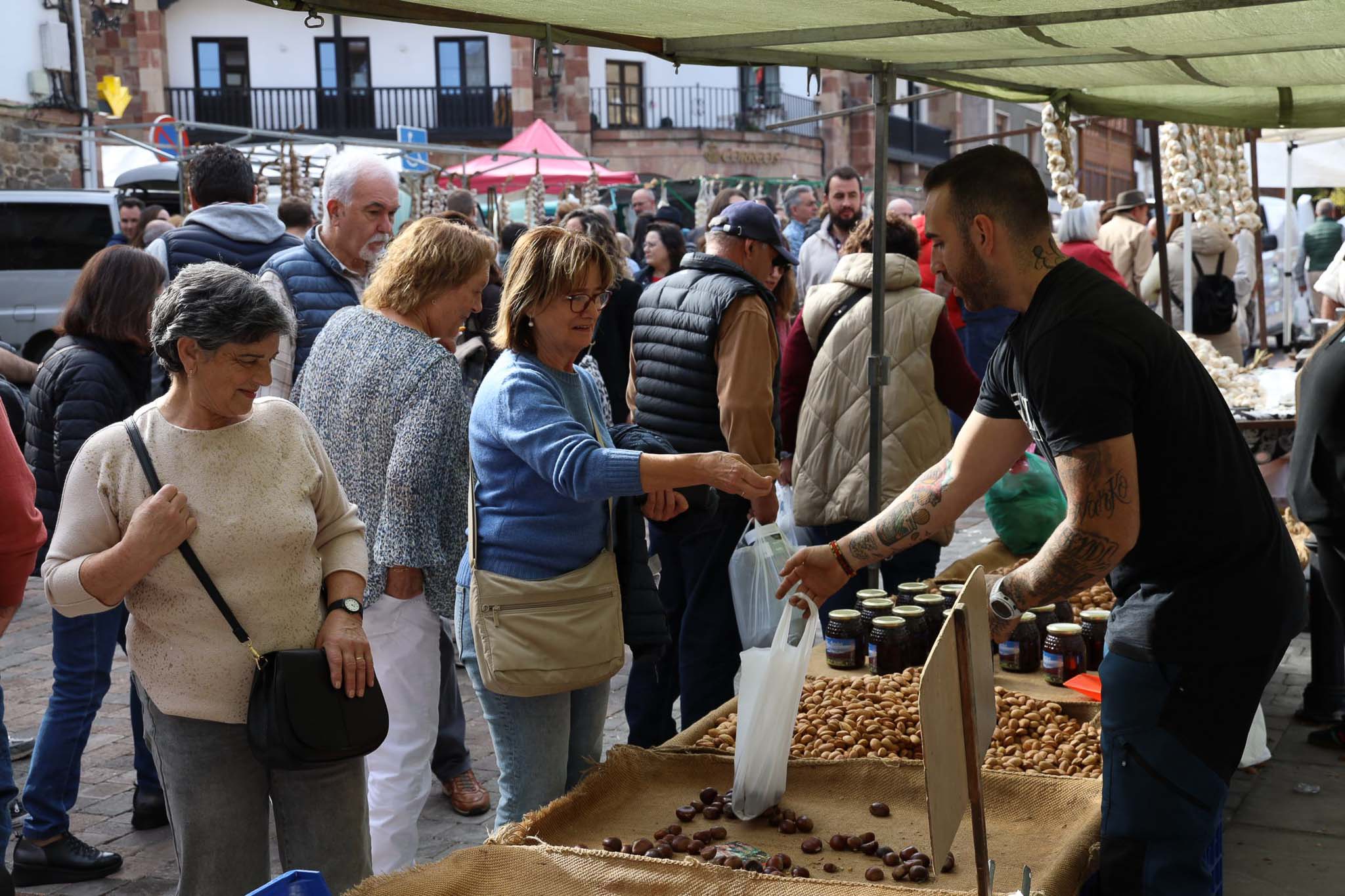 Una mujer adquiere castañas en un puesto de frutos secos.