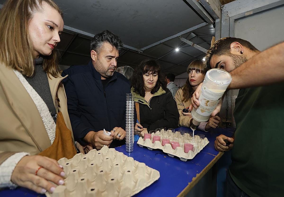 Varias personas observan cómo llenan con orujo los chupitos que se colocan en las típicas hueveras que se utilizan para esta fiesta.