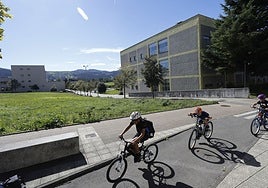 Tres niños circulan con su bicicleta por el campus universitario.