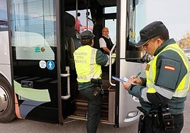 Dos agentes de la Guardia Civil inspeccionan un vehículo de transporte escolar.