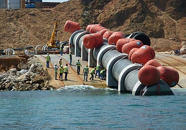 Traslado de una gran tubería para su instalación bajo superficie.