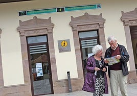 Dos turistas analizan un plano de Comillas delante de la oficina de turismo.