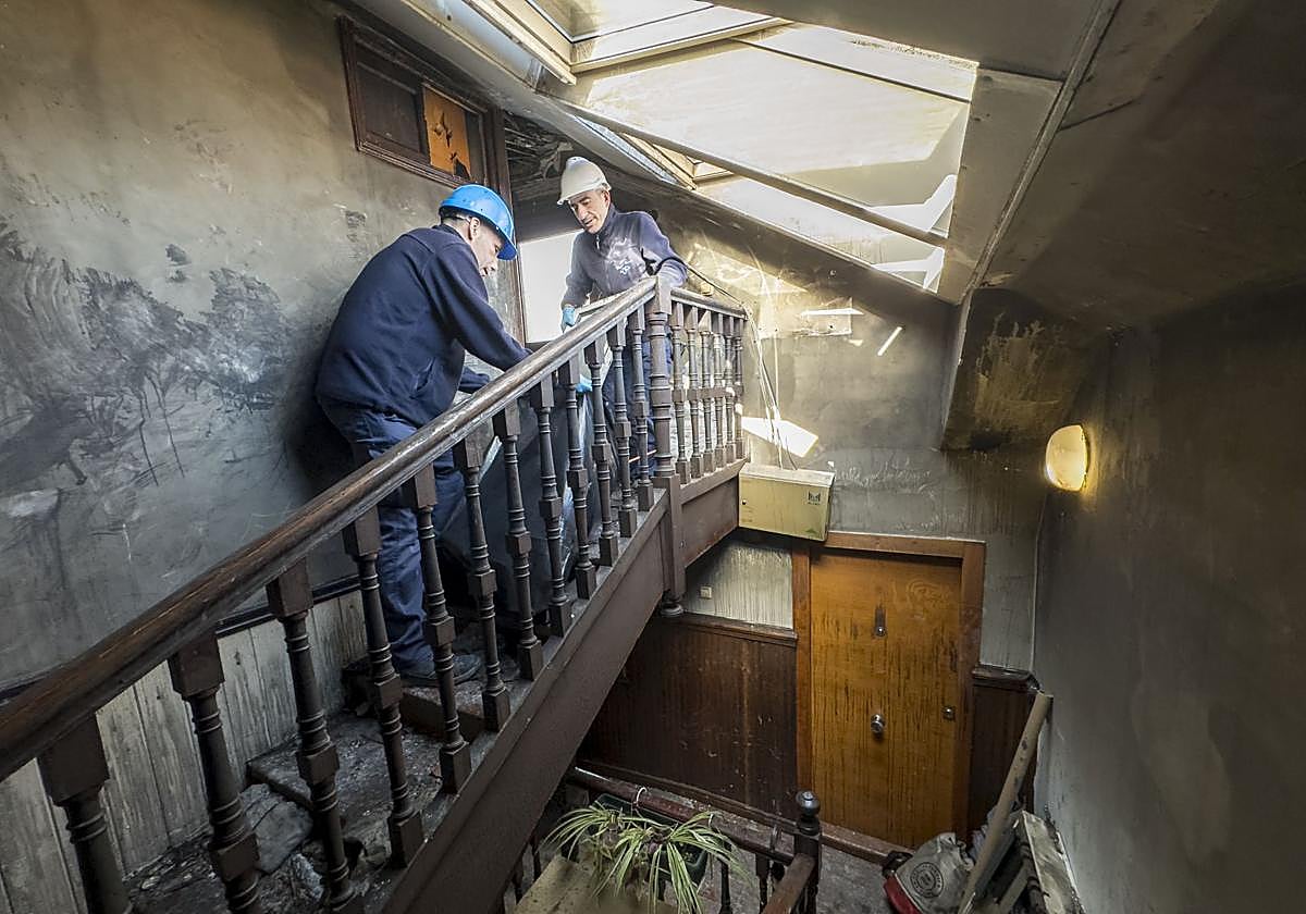 Unos operarios limpian el inmueble afectado por el incendio en el número 33 de Juan de la Cosa.
