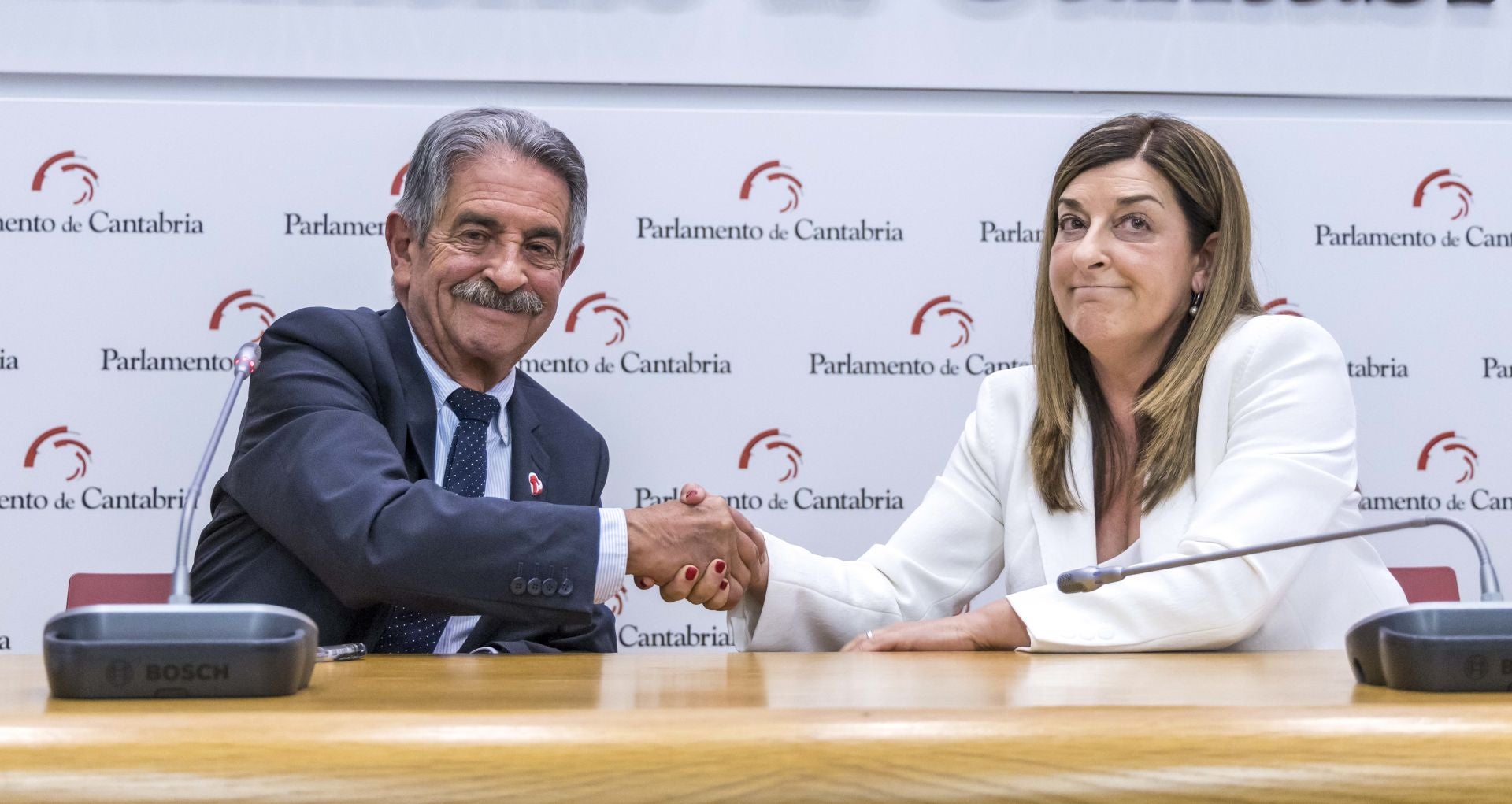 Saludo entre el presidente saliente y la presidenta entrante tras el pacto de investidura.