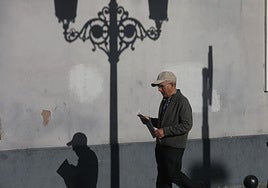 Un jubilado camina con un periódico por la calle.