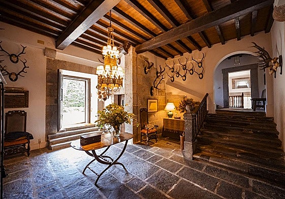 Hall de entrada en el que destaca la sólida escalera de piedra, la colección de cornamentas de la pared y una lámpara que refuerza el carácter noble del inmueble.