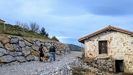 Una pareja pasea por el camino ahora paralizado junto a una cabaña semienterrada por el vial.